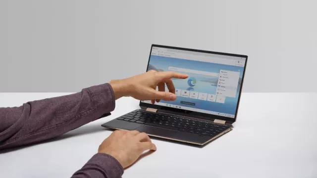 Muž ukazuje prstem na displej laptopu