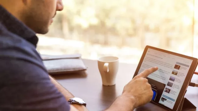 Muž ukazuje na displej laptopu