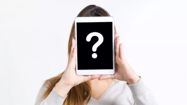 Obličej dívky zakrytý tabletem se zobrazeným otazníkem