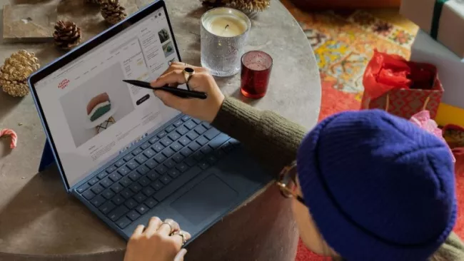 Uživatelka ukazuje tužkou na display laptopu