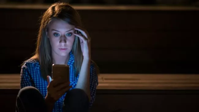 Dívka se smartphonem v ruce a hledící na displej