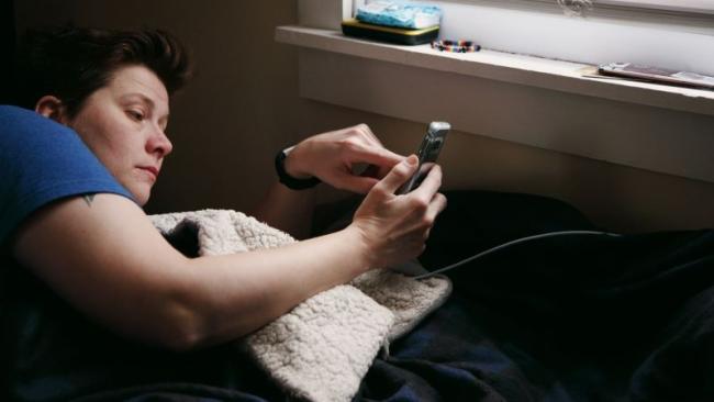 Žena v posteli chatuje na smartphonu
