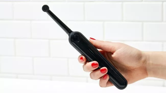 Elektrický zubní kartáček v ruce uživatelky