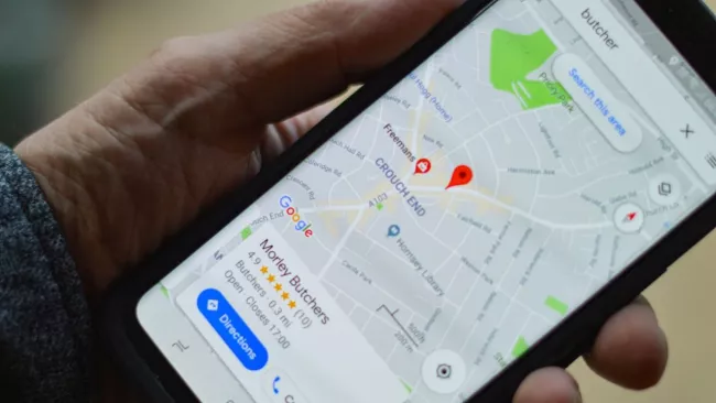 Smartphone se spuštěnou mapovou aplikací v rukou uživatele
