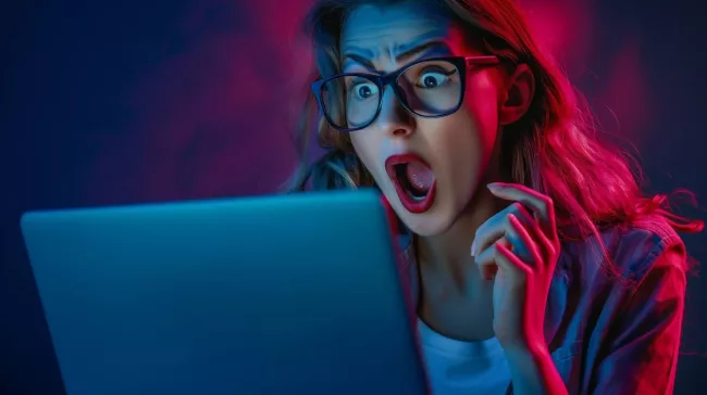 Žena šokovaná tím, co vidí na displeji laptopu