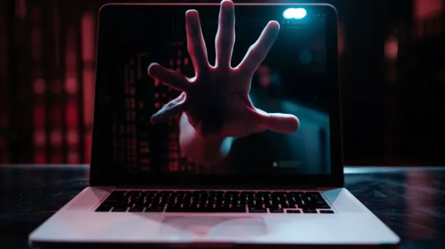 Ruka se natahuje z displeje laptopu a sahá po vás