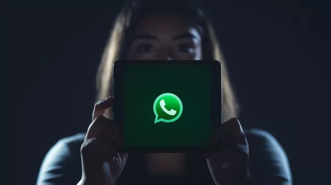 Uživatelka drží v rukou tablet s logem WhatsApp na displeji