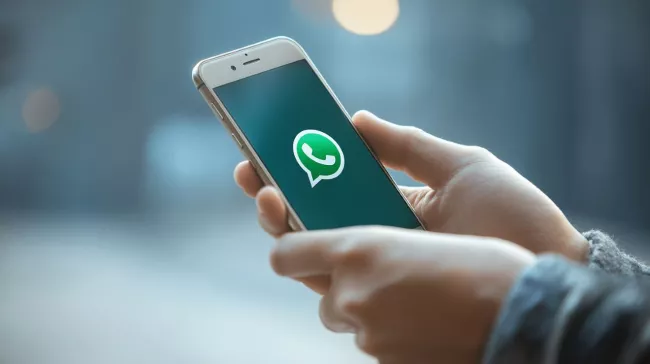 Mobil s logem WhatsApp v rukou uživatelky