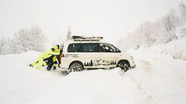 Muži tlačí zapadlý vůz ve sněhu
