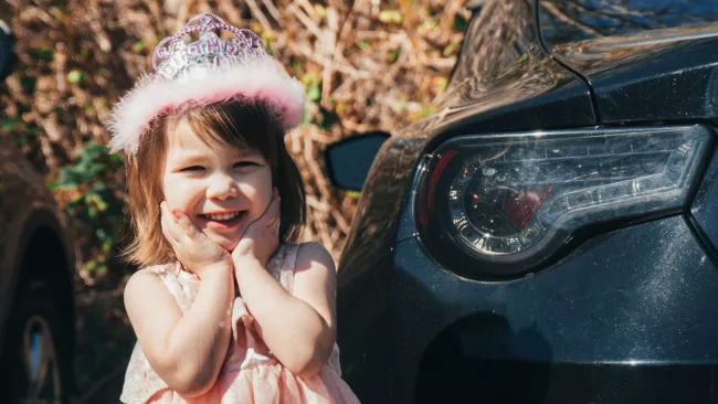 Děvče sedí u černého vozidla