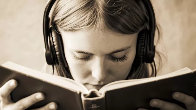 Žena se sluchátky a knihou