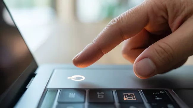 Detail prstu uživatele na spouštěcím tlačítku laptopu