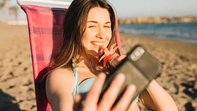 Žena na pláži s telefonem