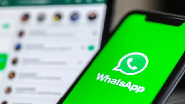 WhatsApp na displeji mobilu a v pozadí konverzace na monitoru