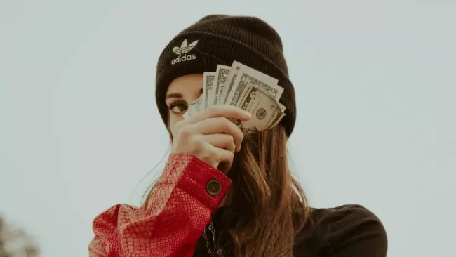 Mladá žena má v ruce vějíř bankovek