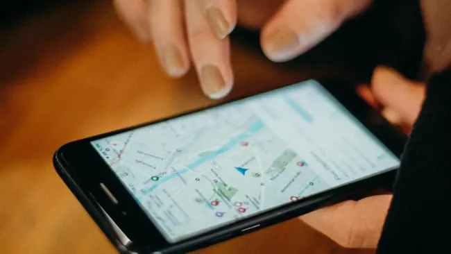 Smartphone s mapovou službou na displeji v rukou uživatelky