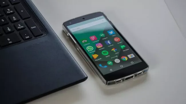 Androidový smartphone na pracovním stole vedle laptopu