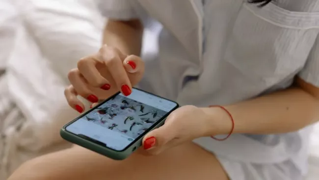 Mladá žena textuje v ložnici