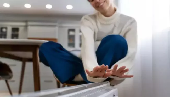 Mladá žena se ohřívá u radiátoru