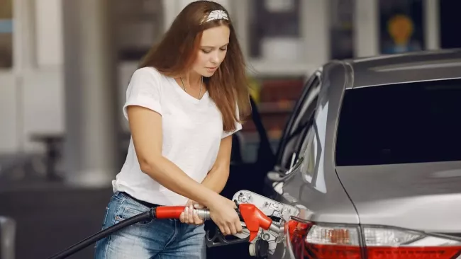 Mladá žena tankuje palivo do svého vozu