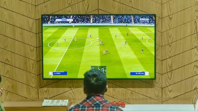 Muž sleduje fotbal na televizi