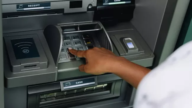 Žena zadává do bankomatu PIN