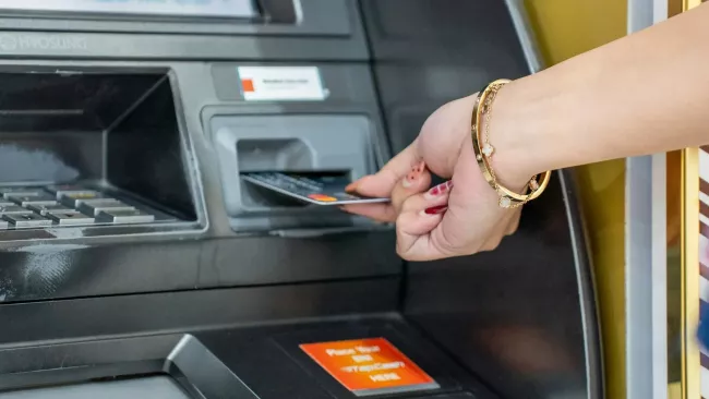 Žena vkládá kartu do bankomatu