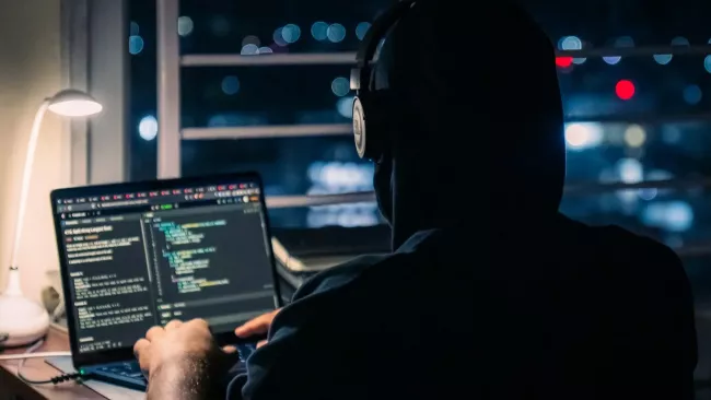 Muž se sluchátky kóduje na laptopu