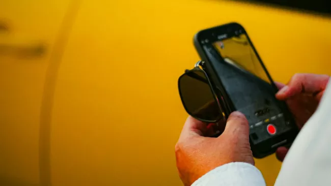 Muž stojí u vozu a má v ruce smartphone