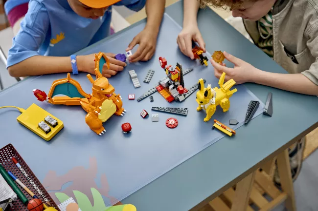 Dvě děti si hrají se stavebnicemi Lego Pokémon.