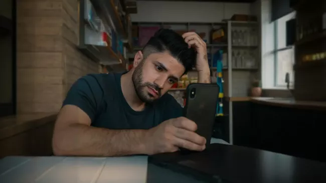 Muž zoufale hledí na svůj smartphone