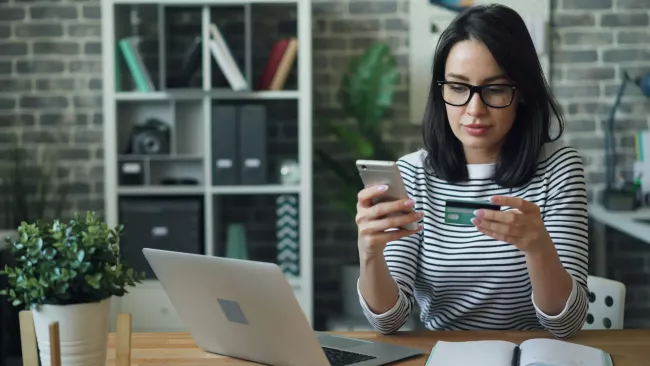 Žena drží v rukou smartphone a platební kartu