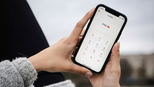 Uživatelka má na displeji svého smartphonu přihlašovací aplikaci mobilního bankingu