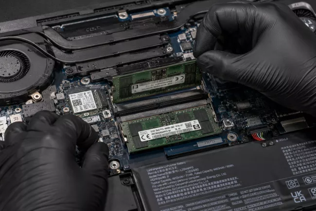 Technik vyjímá modul RAM z otevřeného notebooku.