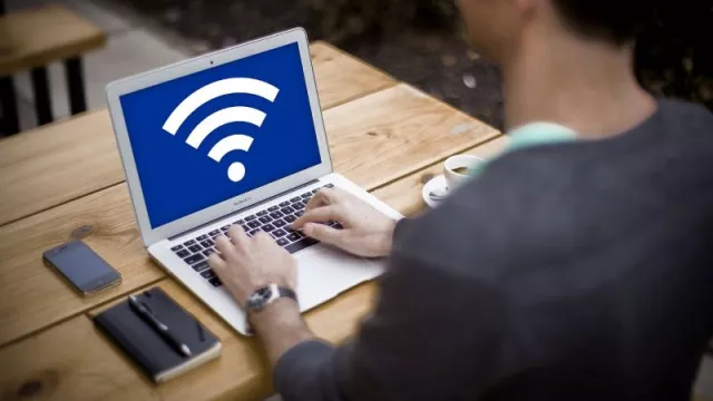 Uživatel u laptopu se symbolem Wi-Fi na displeji