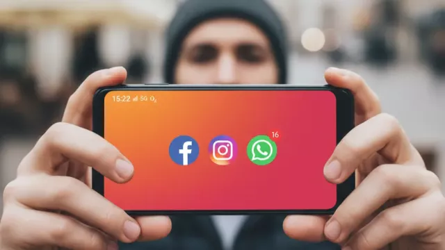 Uživatel drží v ruce mobil a ukazuje sociálně síťové aplikace