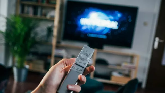 Uživatel má v ruce dálkové ovládání od TV