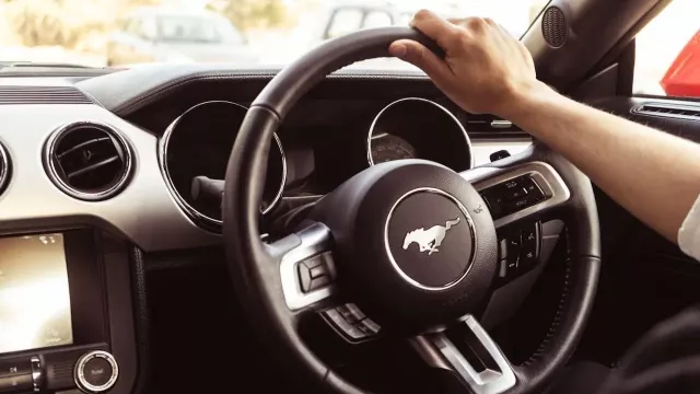Řidič drží v ruce volant svého vozidla