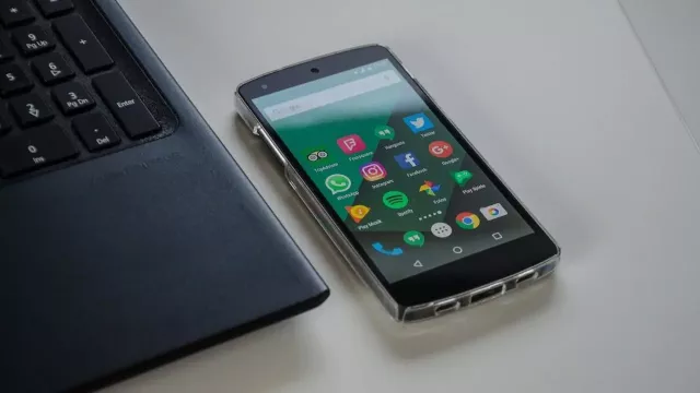 Androidový smartphone na pracovním stole vedle laptopu