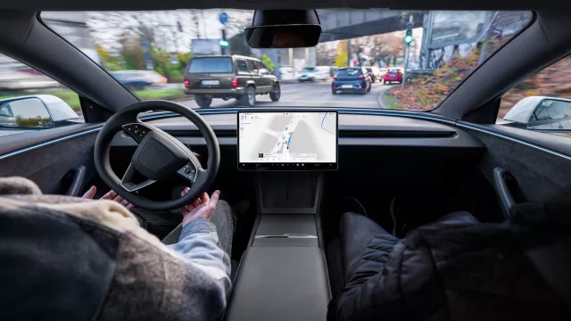 Interiér jedoucího vozu Tesla s výhledem na silnici.